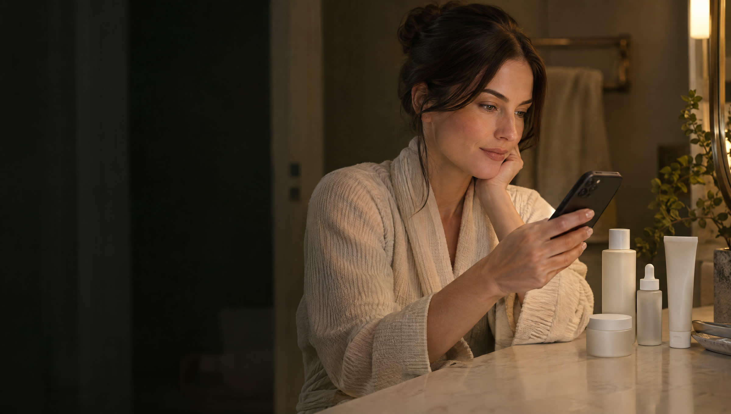 A woman at a bathroom vanity comparing skincare options on her phone